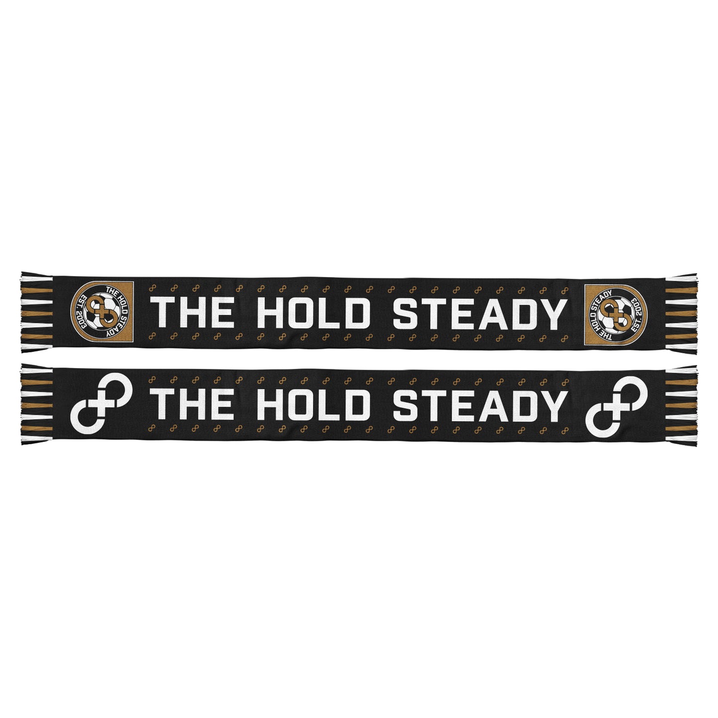 A black The Hold Steady soccer scarf with brown, white, and gold fringes features THE HOLD STEADY in bold white letters. One side shows the band logo and "Unified Scene"; the other has interlocking circles.