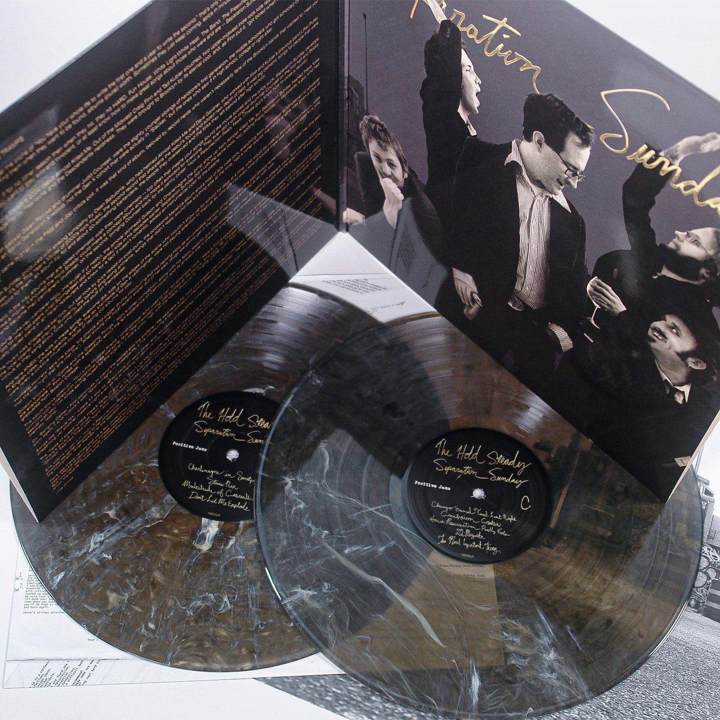 The Hold Steady's 20th Anniversary Edition of Separation Sunday features two gray-and-white marbled vinyl records with sleeves, including a main sleeve displaying a black-and-white photo of five men.