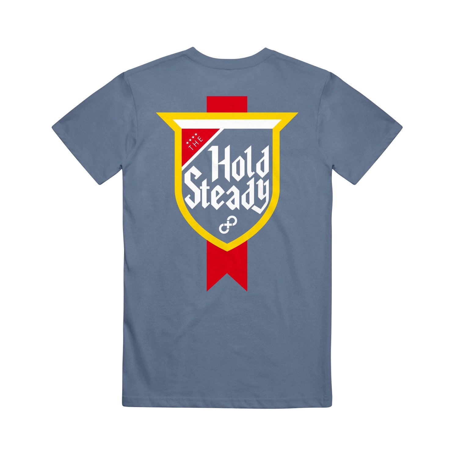 A blue Comfort Colors tee from The Hold Steady, featuring a bold shield emblem on the back with a yellow border, red vertical ribbon, and white stylized “The Hold Steady” text.