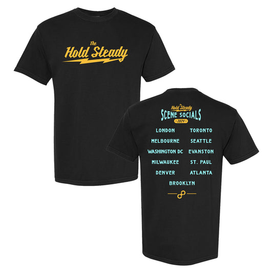 This black The Hold Steady Comfort Colors T-shirt features the band’s name in yellow on the front. On the back, “Scene Socials 2024” appears over a blue and yellow city list, including London, Toronto, Seattle, and Milwaukee.